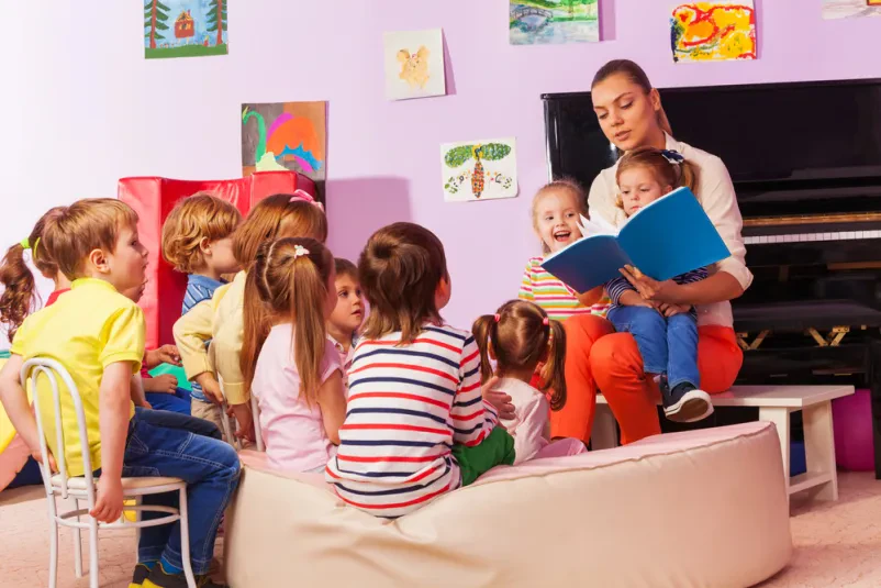 Ženska bere pravljice otrokom ob klavirju