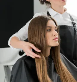 Bližnji posnetek mlade ženske z dolgimi, sijočimi in skrbno oblikovanimi lasmi, ki poudarjajo njeno naravno lepoto.