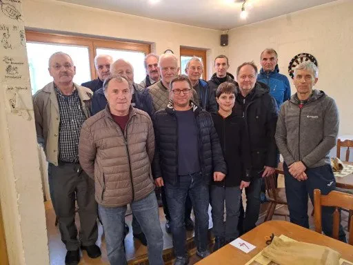 Skupina otrok in mladostnikov se zbrano posveča šahovski igri. Prikazan je aktiven trening in učenje šaha Idrija, okolica, kar kaže na živahno klubsko dejavnost.