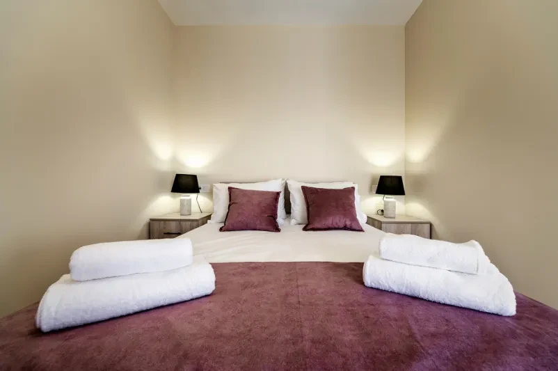 Udobna spalnica z zakonsko posteljo in mehkimi blazinami Moderna spalnica z udobno zakonsko posteljo, blazinami in nočnimi omaricami. Odličen ugoden apartma za 2 osebi Ljubljana za sproščujoč oddih.