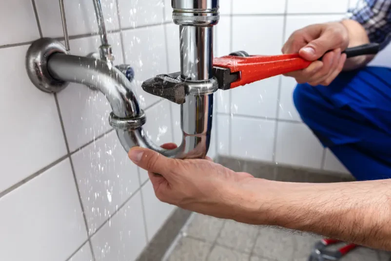 Moška roka vodovodarja z nastavljivim ključem strokovno popravlja puščanje na odtokih, zagotavljamo kvalitetne Vodovodne inštalacije in iskanje napak na inštalacijah Ljubljana.