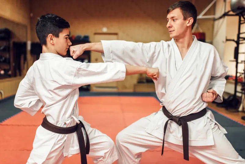 Mojstra karata na treningu v telovadnici Dva mojstra karata v belih kimonih s črnimi pasovi trenirata v telovadnici. Odličen prikaz za klub Borilne veščine Ljubljana Jarše.