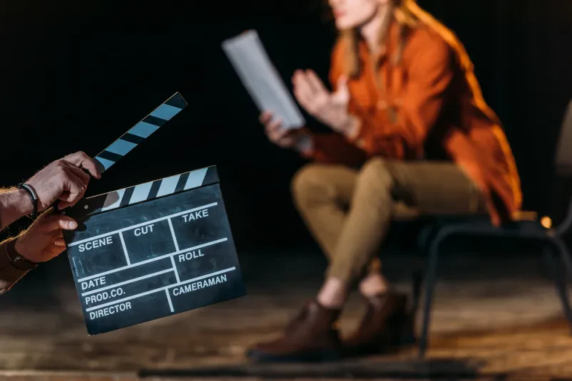 Moški igralec drži filmsko klapo, pripravljen za začetek prizora. Išče se dober igralec za reklame, serije in filme v Sloveniji.