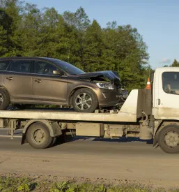 Vlečni tovornjak odvaža poškodovan avto po nesreči, kar ponazarja ključno vlogo hitre avtovleke v Brežicah, Posavju.