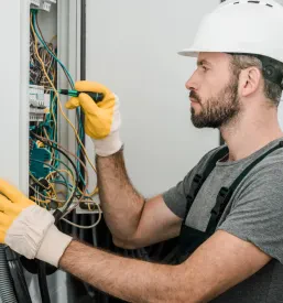 Električar popravlja omarico. To je primer Kvalitetne obnove in servisa elektroinštalacij Ljubljana, okolica.