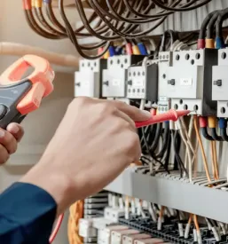 Inženir z multimetrom preverja električne inštalacije v krmilni omari. To zagotavlja Kvalitetne elektroinštaalcije Hajdina, Podravje.