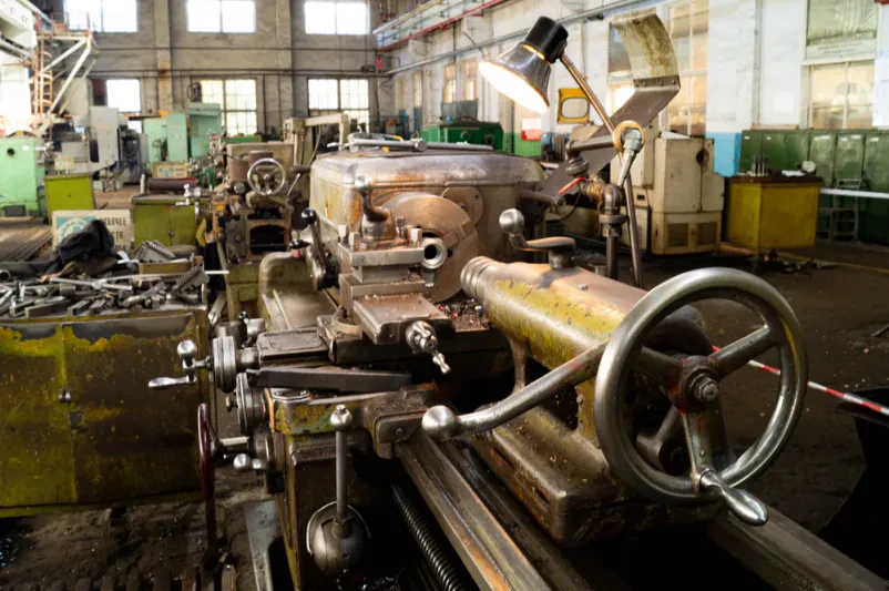 Krmilne ročice stroja za obdelavo kovin v industrijski delav Detajl krmilnih ročic in gumbov na industrijskem stroju, ki omogoča precizno obdelavo kovin v proizvodnem obratu.