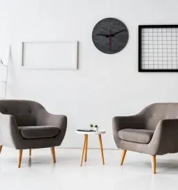 Moderna, svetla čakalnica s sivimi oblazinjenimi naslanjači in elegantno klubsko mizico, ki predstavlja udobno pisarniško pohištvo po meri, primerno za Dekane na Obali.