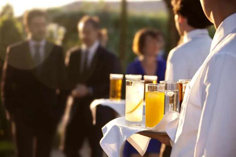 Profesionalna ekipa streže osvežilne pijače in kanapeje gostom na prireditvi, kar je ključno za uspešen catering za dogodke Štajerska.