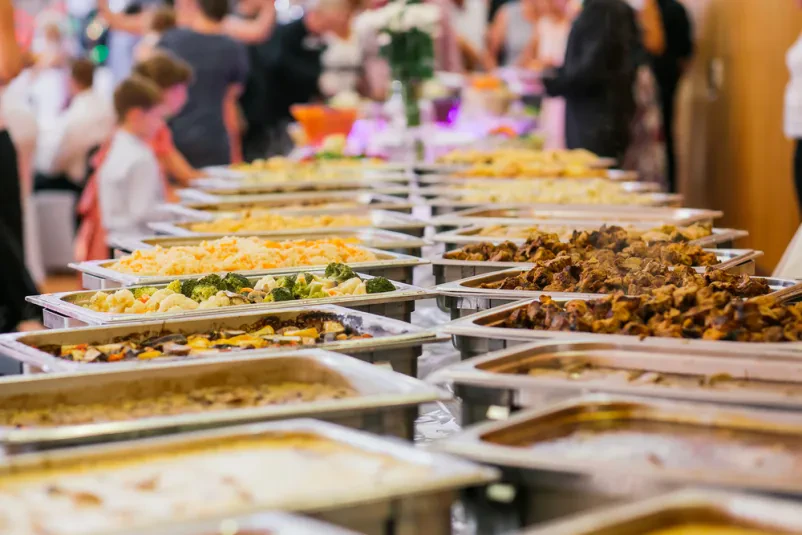 Bogat poročni buffet s pestro izbiro jedi, vključno s predjedmi, glavnimi jedmi in sladicami, ki so skrbno pripravljene za praznovanje.