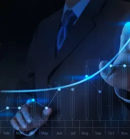 Poslovneževa roka se dotika interaktivnega virtualnega grafa, ki prikazuje poslovne podatke in finančno rast. To je odličen primer uporabe najboljšega consultinga za podjetja pri izdelavi analiz in spremljanju uspešnosti.