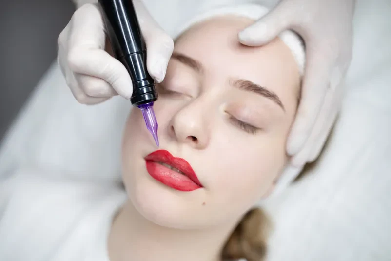 Strokovnjakinja skrbno nanaša permanentni make-up na ustnice, kar zagotavlja dolgotrajen in naraven videz.