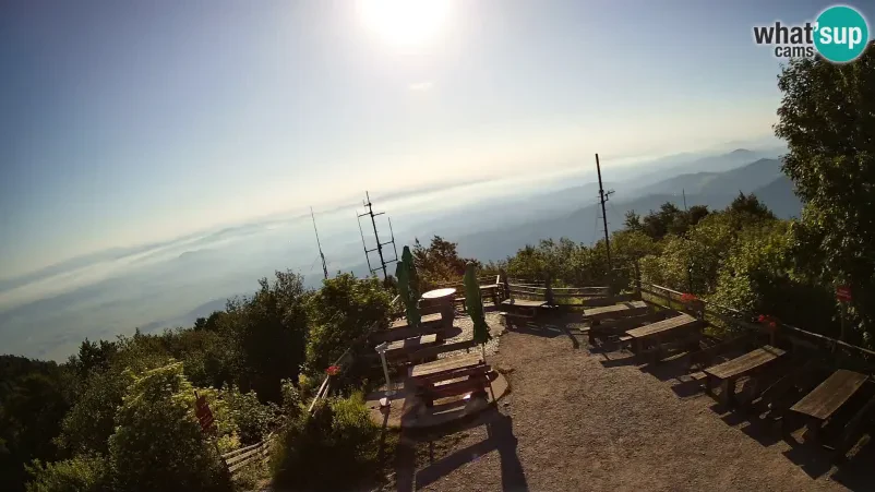 Panoramski pogled z lokacije Širok panoramski pogled na naravno okolico in bližnje vrhove, ujet iz predela okoli planinske koče, ki prikazuje lepoto pokrajine.