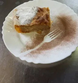Tradicionalna slovenska gibanica z bogato nadevko, postrežena na mizi, ki ponosno predstavlja domače jedi in sladice planinske koče.