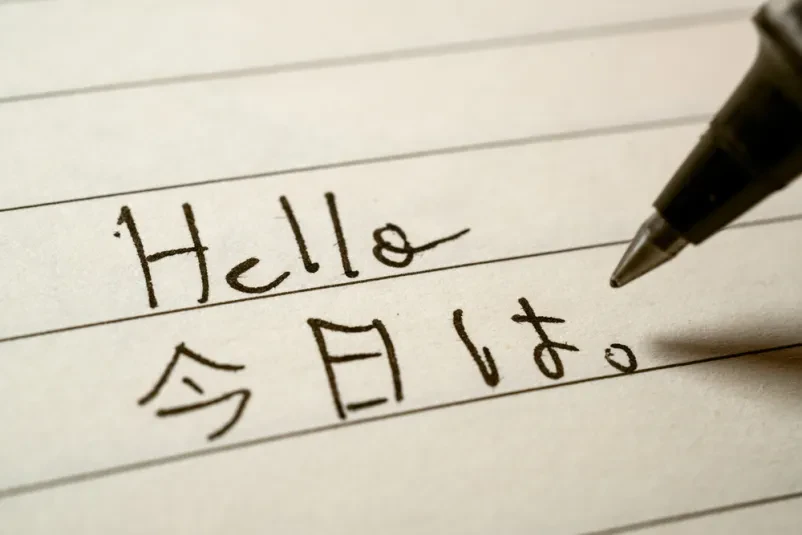 Začetnik piše japonske kanjije Posnetek od blizu prikazuje začetnika, ki v zvezek zapisuje japonske kanji znake, kar je pomemben del učenja japonske kulture in jezika.
