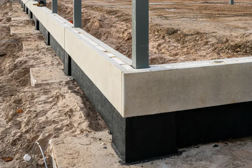 Temelji betonske novogradnje z jeklenimi stebri. Statični izračuni za novogradnje so ključni za stabilnost in varnost objekta.