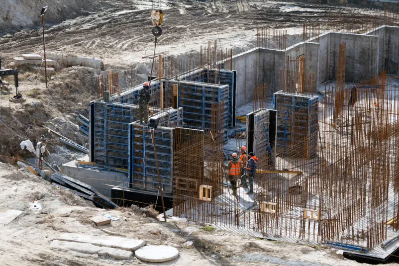 Delavec pripravlja armaturo za nosilne stene. Precizna postavitev je bistvena za trdnost in stabilnost betonske konstrukcije ter celotne zgradbe.