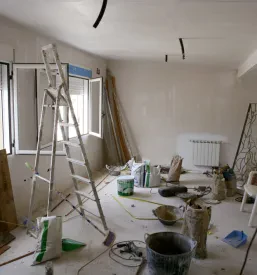 Razmetana soba med obnovo prikazuje gradbene materiale in orodje, pripravljeno za adaptacijo in izboljšanje prostora.