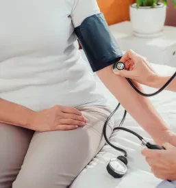 Medicina in skrb: medicinska sestra meri krvni tlak starejši pacientki, kar je pomemben del zdravstvene oskrbe.