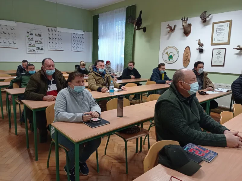 Veseli otroci in odrasli prejemajo potrdila za uspešno opravljeno šolanje in delo s psi, kar poudarja pomen izobraževanja.