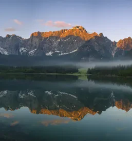 Čudovit razgled na bistro gorsko jezero, obkroženo z gostimi gozdovi in strmimi vrhovi Julijskih Alp.