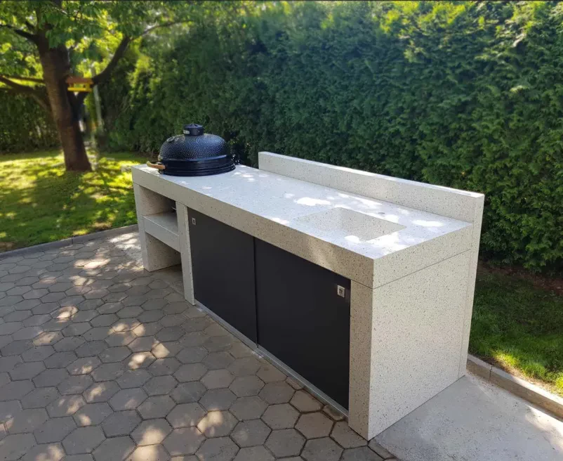Elegantna letna kuhinja z betonskim pultom, popolna za uživanje na prostem. Prikazuje vrhunsko Izdelavo in montažo betonskih komponent za dvorišča Slovenija.