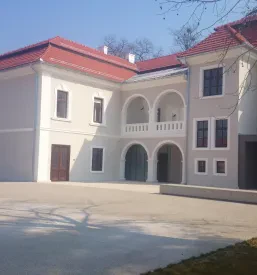 Monumentalni vhod v Dvorec Sternthal, poudarjen z natančno oblikovanimi betonskimi potmi in elegantnimi arhitekturnimi detajli.