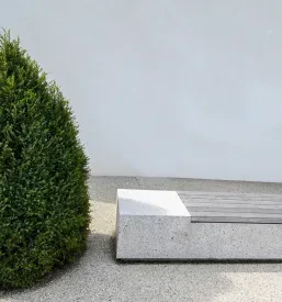 Prostran moderno urejen zunanji prostor z inovativnimi betonskimi klopmi in urejeno okolico, idealen za sproščanje.
