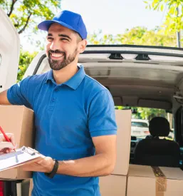 Prijazen kurir izroča paket stranki, ki potrjuje prejem. Učinkovita lokalna kurirska dostava blaga z avtom Celje in okolica.