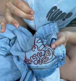 Prikaz natančnega dela pri šivanju na šivalnem stroju, kjer nastajajo edinstveni in personalizirani izdelki.