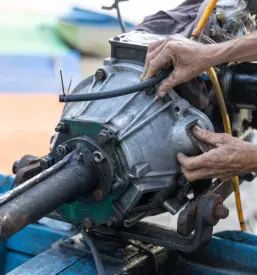 Mehanik se osredotočeno posveča popravilu izvenkrmnega motorja na leseni ribiški barki. Poudarek je na vzdrževalnih delih pogonskega sistema na morskem plovilu.