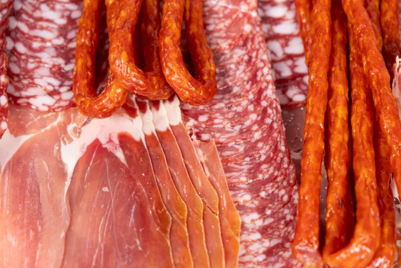 Pester izbor španskih suhih mesnin Estetsko urejen pladenj z narezanimi suhimi mesninami, kot so španski pršut in salame, odlično za prodajo suhomesnatih izdelkov Domžale.
