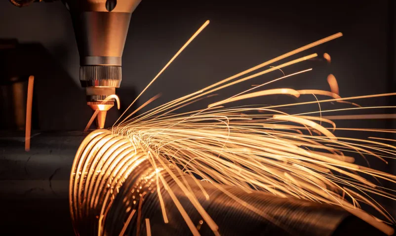 Industrijski laserski stroj s CNC krmiljenjem natančno reže kovino, ustvarjajoč iskre med obdelavo.