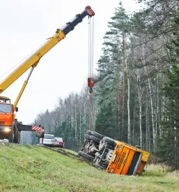 Poškodovan tovornjak leži ob robu avtoceste po nesreči, kar kaže na potrebo po strokovni pomoči in odvozu vozila.