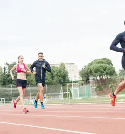 Skupina mladih atletov teče po rdeči atletski stezi. Skupinski trening je bistveni del šole atletike Borovnica.