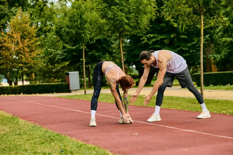 Trening atletike z osebnim trenerjem Odločna športnica trenira na atletski stezi, pri čemer jo vodi osebni trener. Idealno za šolo atletike Borovnica.