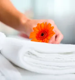 Čistilka skrbno pripravlja postelje v čisti hotelski sobi, kar je znak kakovostne sobodajalke. To priča o urejenih in ugodnih sobah Prestranek.