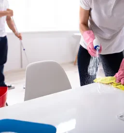 Dva čistilca skrbno opravljata delo v pisarni, eden pomiva tla z mopom, drugi pa briše mizo, kar kaže na učinkovitost ugodnega čiščenja blokov Postojna.