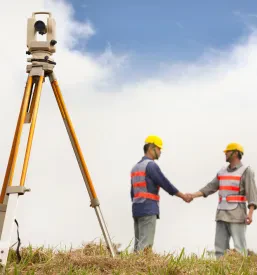 Dva geodetska inženirja se rokujeta na terenu