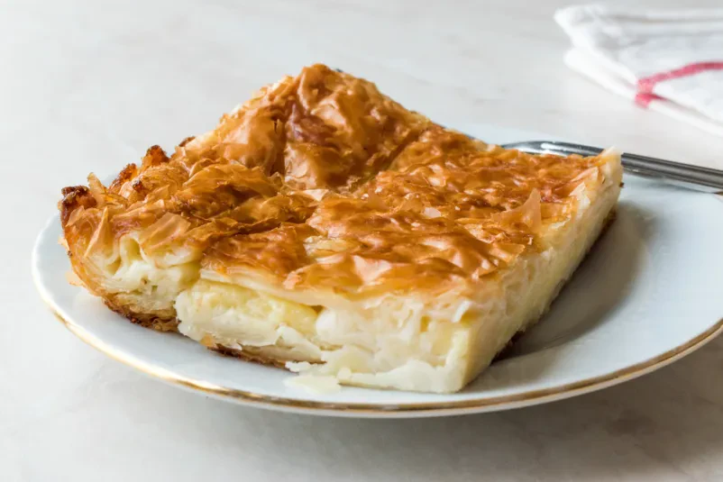 Tradicionalni turški borek na lesenem pladnju Sveže pripravljen okrogel turški burek na lesenem pladnju, s hrustljavo zlato skorjico. Takšen dober burek Komenda je idealen za hitro in okusno malico.