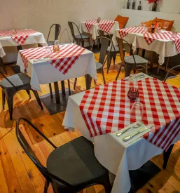 Prijeten in sodobno opremljen prostor restavracije v italijanskem slogu, s pripravljenimi mizami in stoli, ki čakajo na goste. Idealno za zaključene družbe in praznovanja.