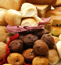 Privlačna kolekcija sladkega in slanega pekovskega peciva, kot so muffini in pite, urejeno razstavljena na čistem belem ozadju.
