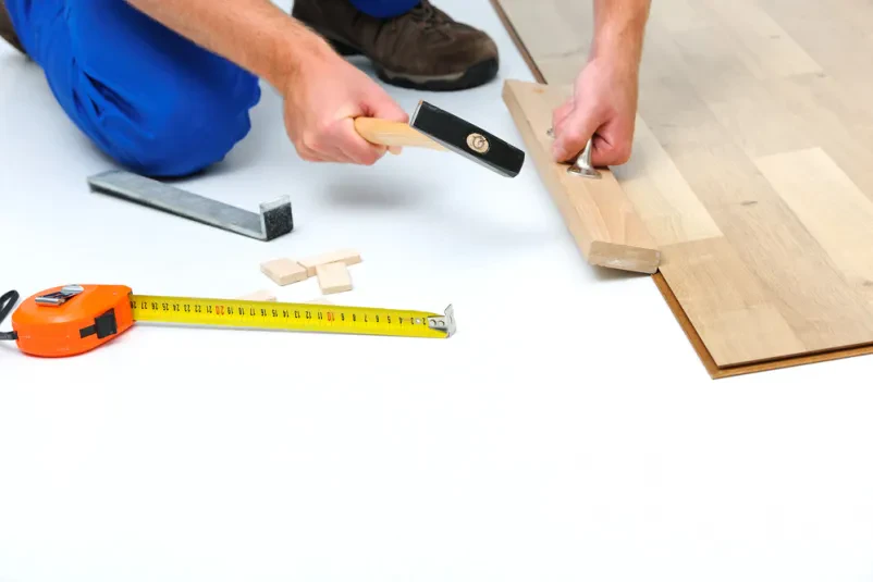 Delavec skrbno namešča laminatne plošče v prostor. Polaganje laminata in vinila Pomurje, Štajerska za trajnostne rešitve.