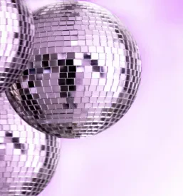 Skupina bleščečih retro disco krogel s svetlimi odsevi, postavljenih na živo rdeči podlagi, ki je kot nalašč za poudarek na energiji in vzdušju dogodka Retro disco Slovenija.
