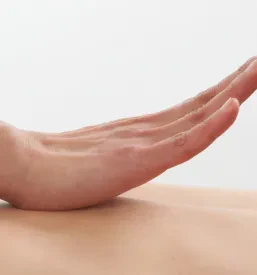 Podroben posnetek rok maserja, ki z oljem in nežnimi gibi masira hrbet stranke, kar prinaša takojšnje olajšanje.