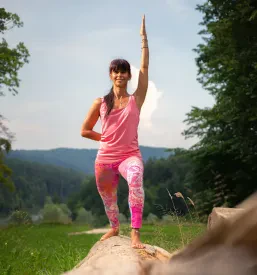 Voditeljica joge v položaju bojevnika vodi tečajnice na uri joge, ki poteka v Škofji Loki.